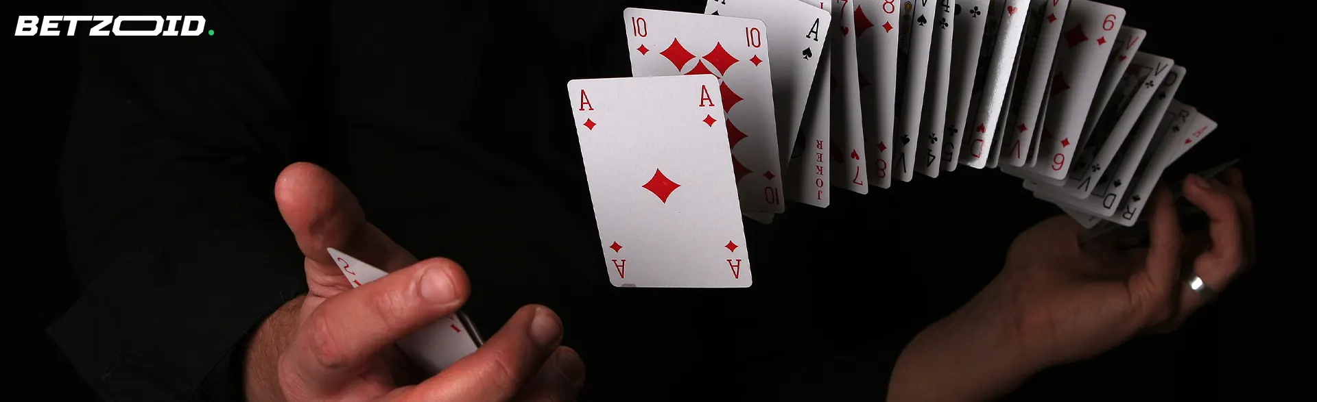 A man shuffles a deck of cards in the air.