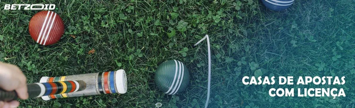 Macete de croquet e bolas na grama.