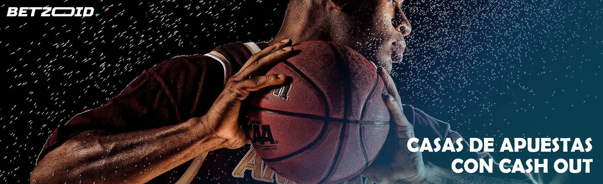 El jugador de baloncesto sostiene el balón en sus manos sobre un fondo oscuro.