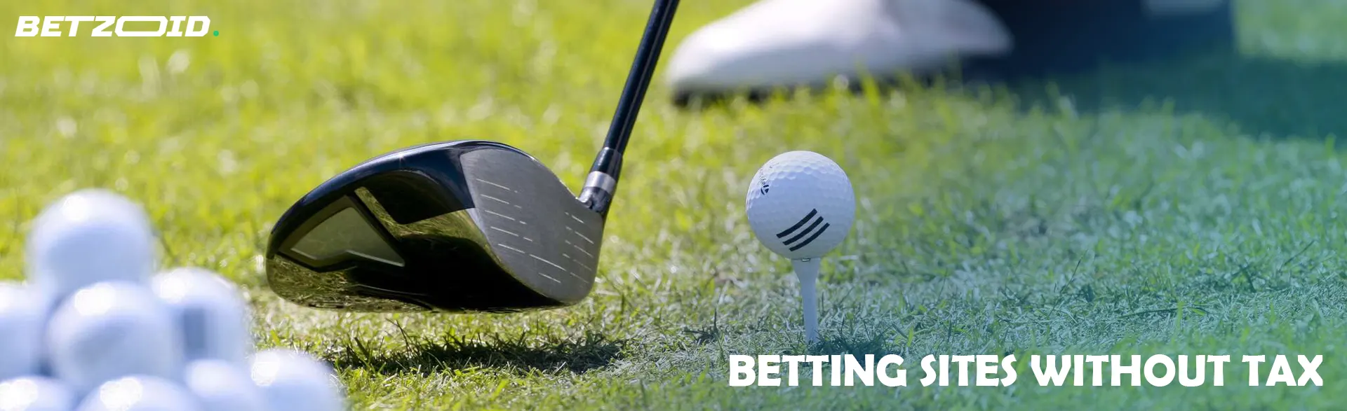 A golf putter next to balls on the grass.