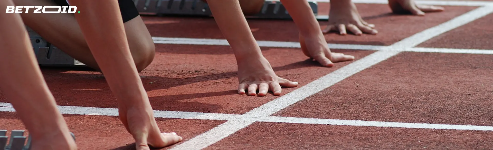 Runners' hands and feet poised on the starting line of a track race.