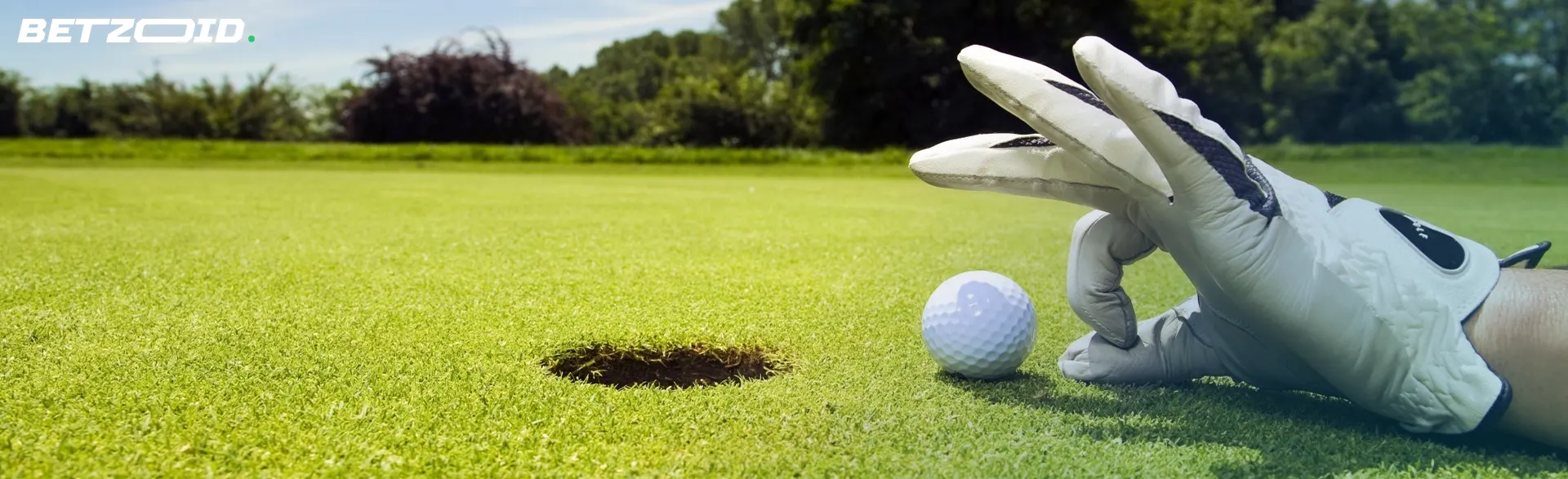 A player helps roll a golf ball into the hole.