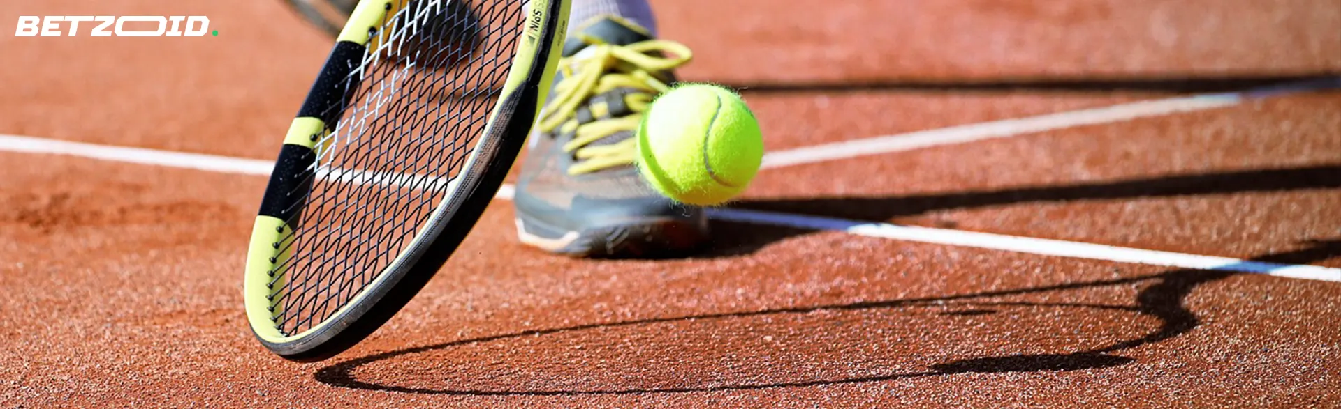 Tennis racket and ball on a clay court.