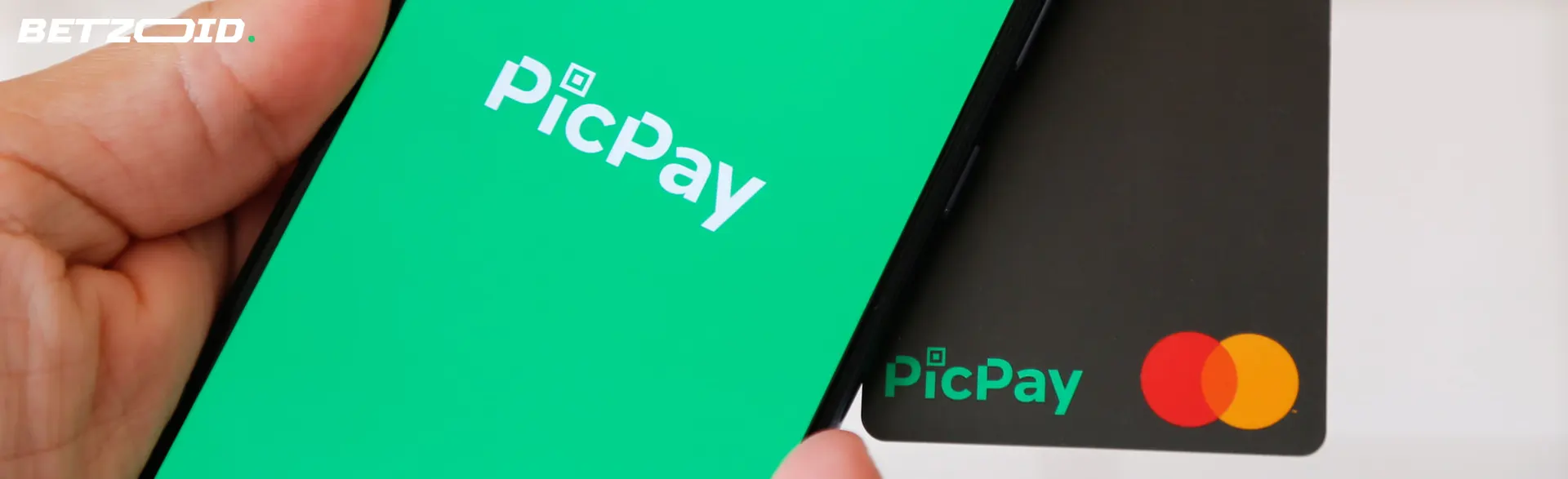 Logotipo PicPay no smartphone e cartão bancário.