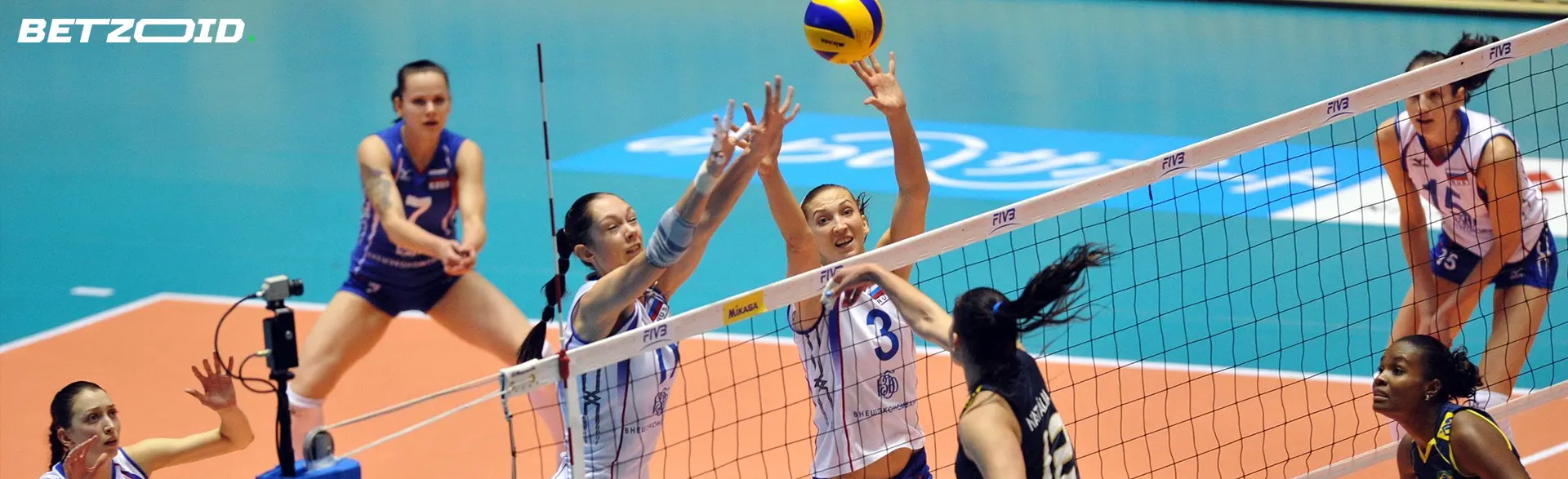 Los jugadores de voleibol intentan bloquear el balón en la red.