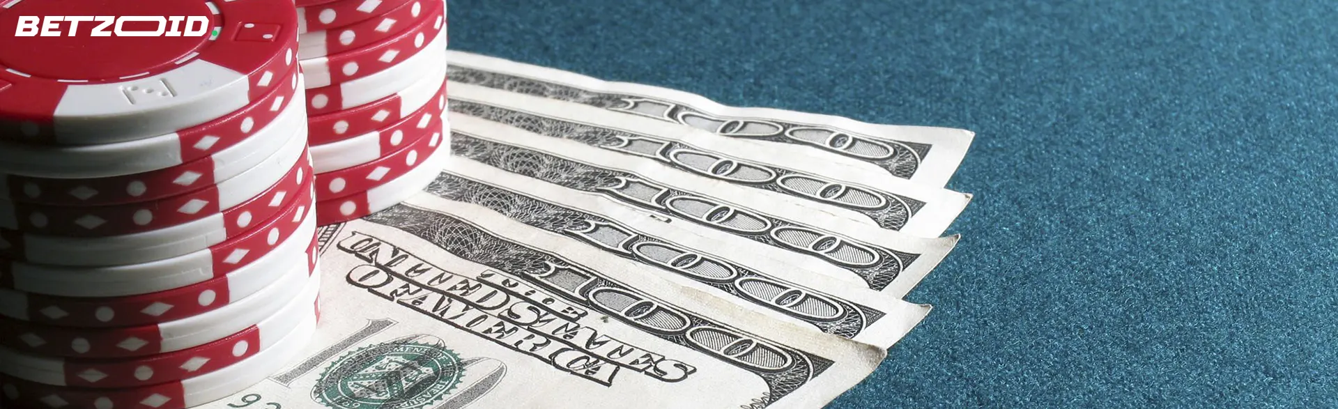 White casino chips placed on top of several 100-dollar bills.