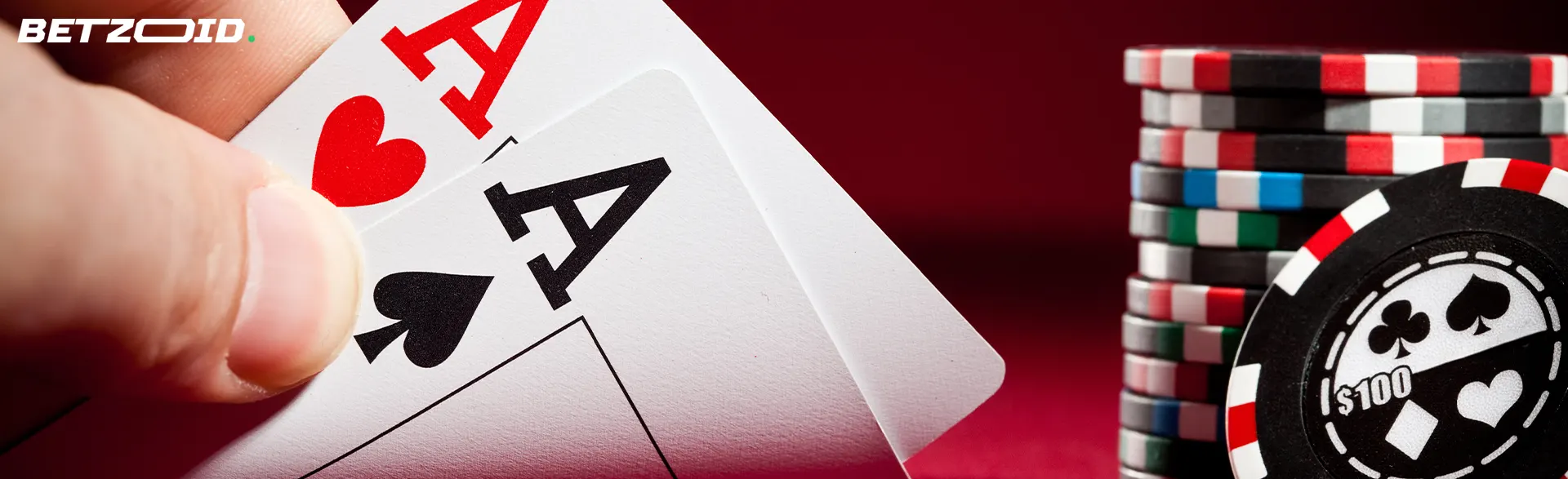 Pelaaja pitää kortteja kädessään kasinon pelimerkkien vieressä.