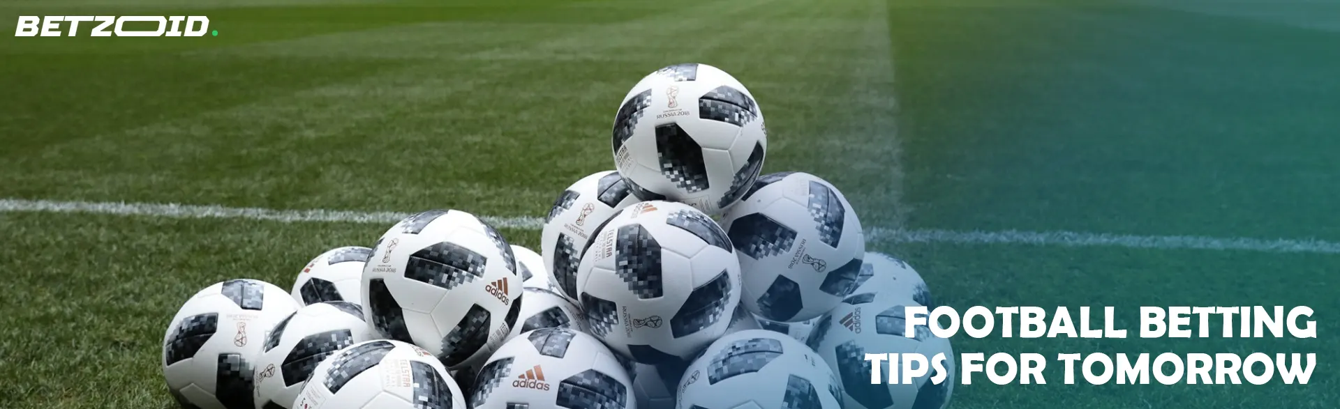 Soccer balls are stacked in a pyramid on the field.