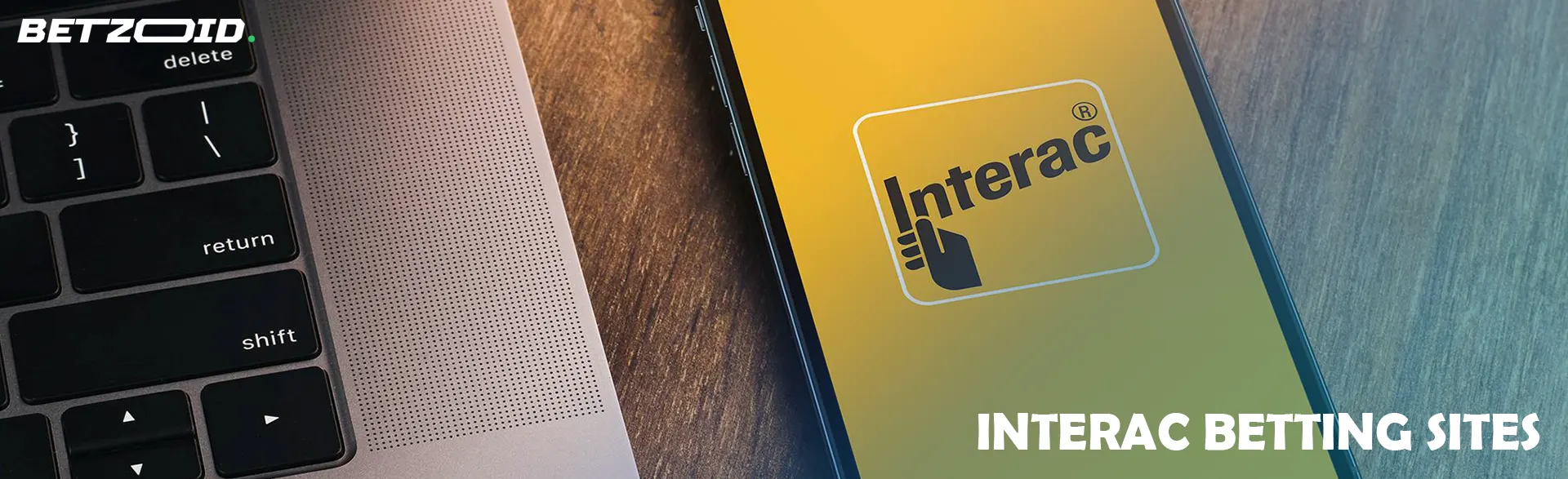 A smartphone screen with the Interac logo next to a laptop keyboard.