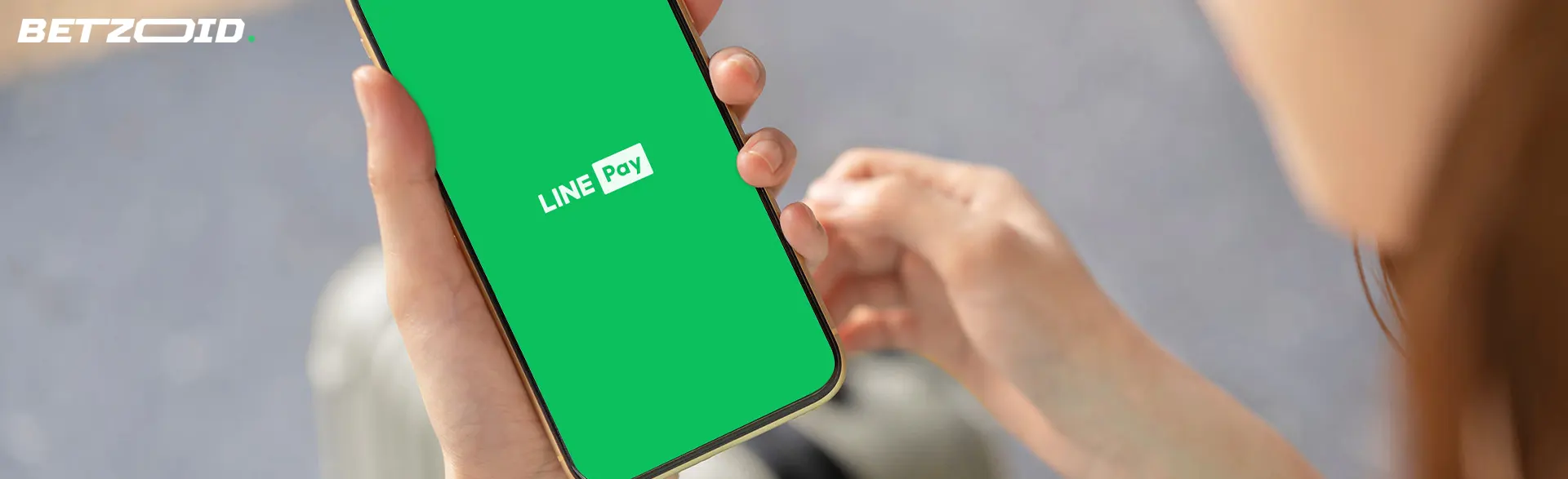 男性がline payのロゴが入ったスマートフォンを持っています。