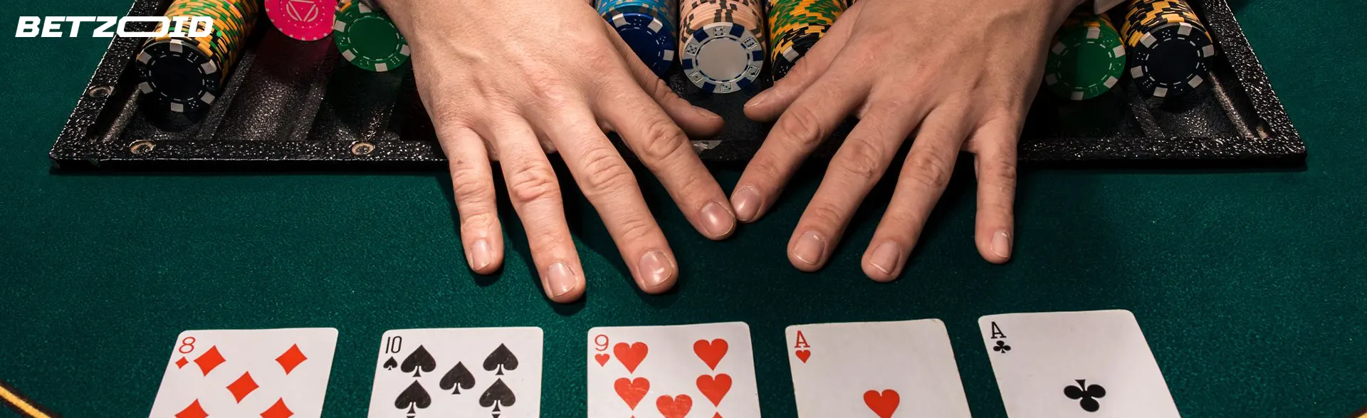 Player's hands next to cards and chips on casino table.