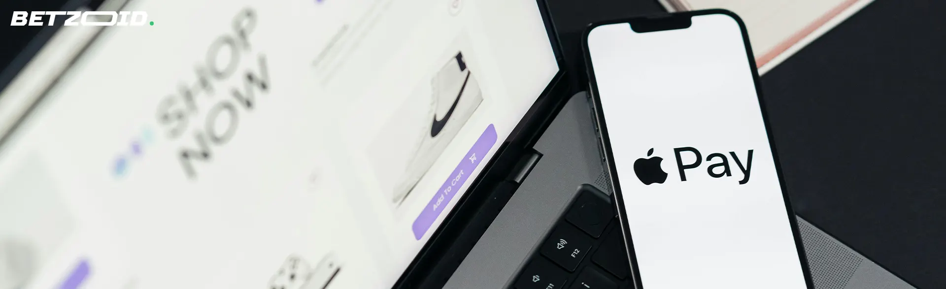 Un smartphone avec le logo Apple Pay repose sur un ordinateur portable.