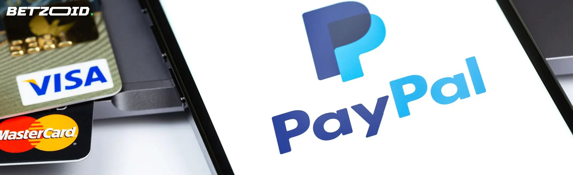 Logo PayPal na smartfonie obok kart bankowych.