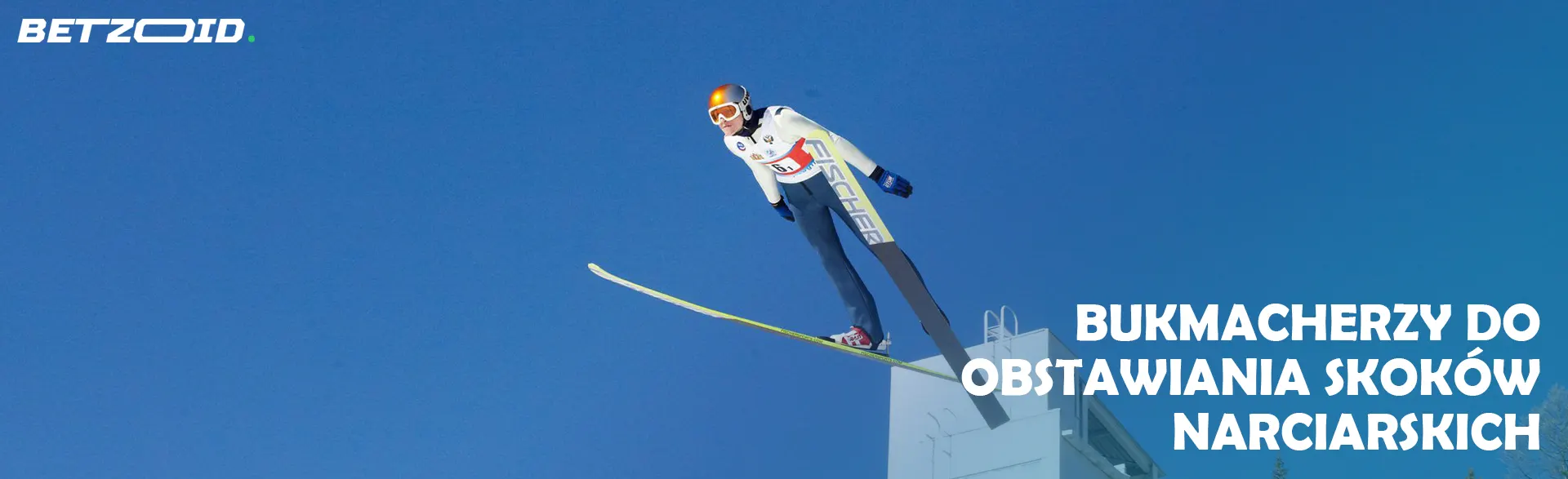 Skoczek narciarski w powietrzu na tle błękitnego nieba.