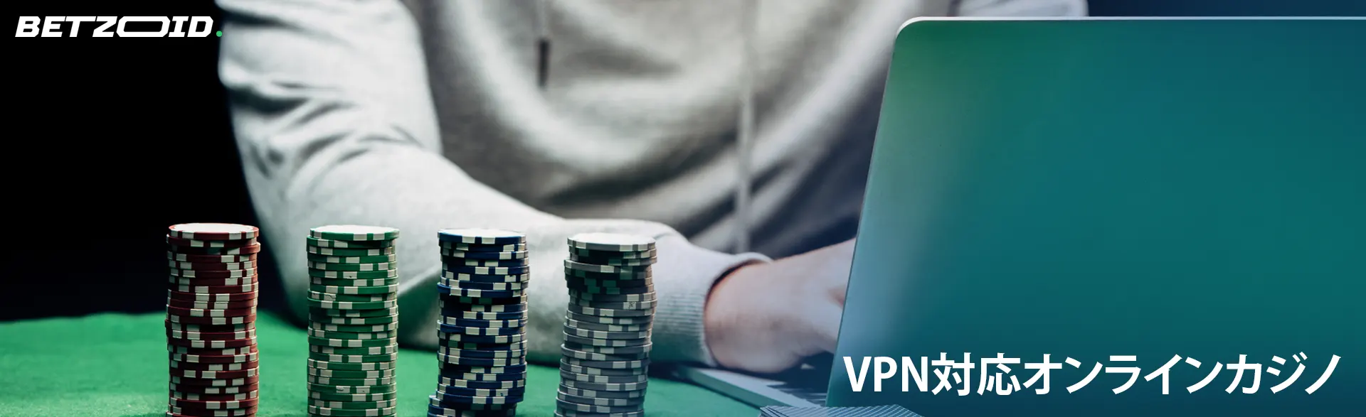 カジノチップの隣にあるラップトップの後ろにいるプレーヤー。